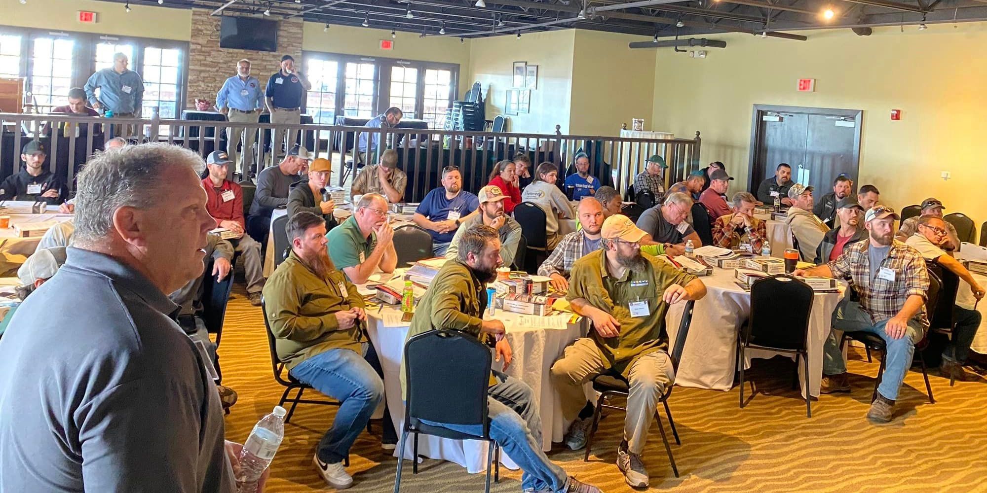 A group of wildlife control operators in a large room listening to a NWCOA training seminar.