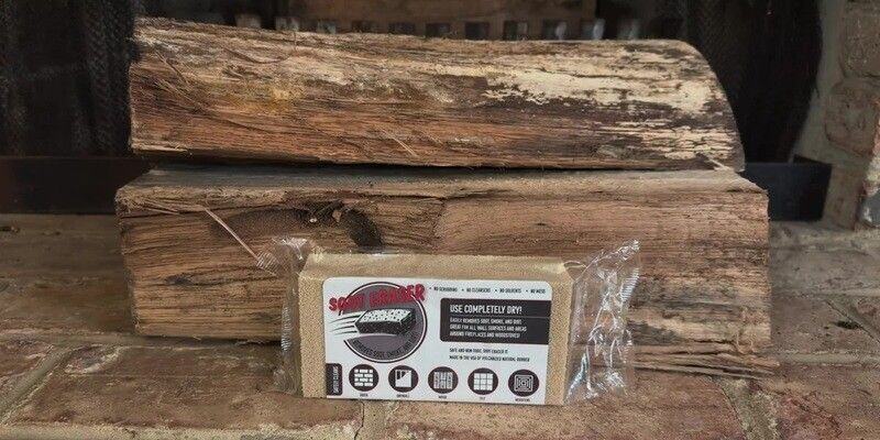 A pile of logs sitting just outside a fireplace. Propped up in front of the logs is a HY-C Soot Eraser.