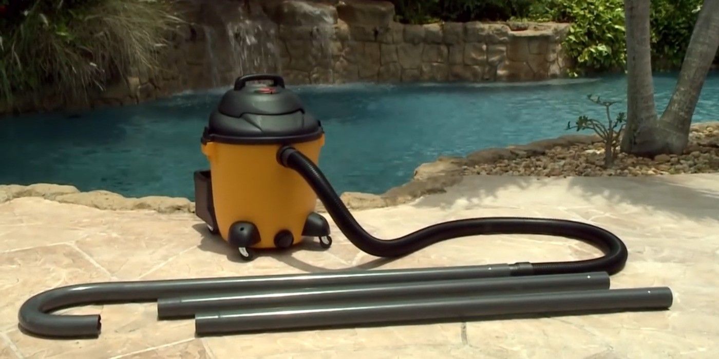 A Gutter Clutter Buster tool connected to a yellow wet/dry vacuum with a nicely landscaped pool in the background.