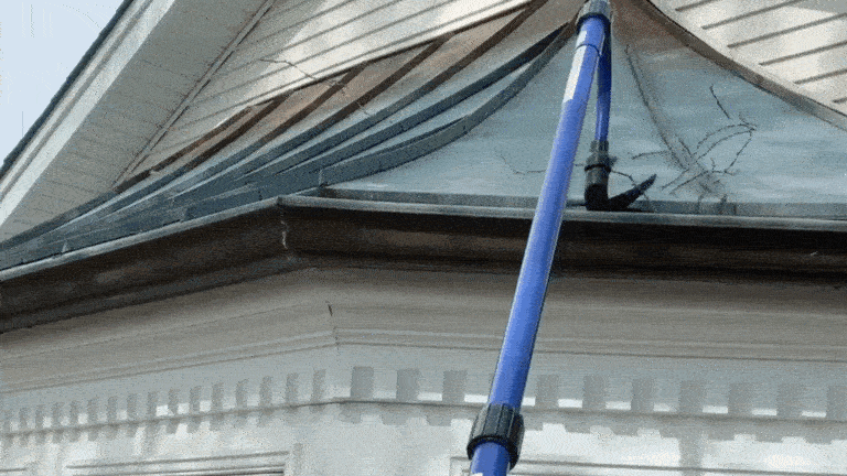 A GIF demonstrating both the paddle brush and nozzle brush functions of the Gardus GutterSweep on a home's gutters
