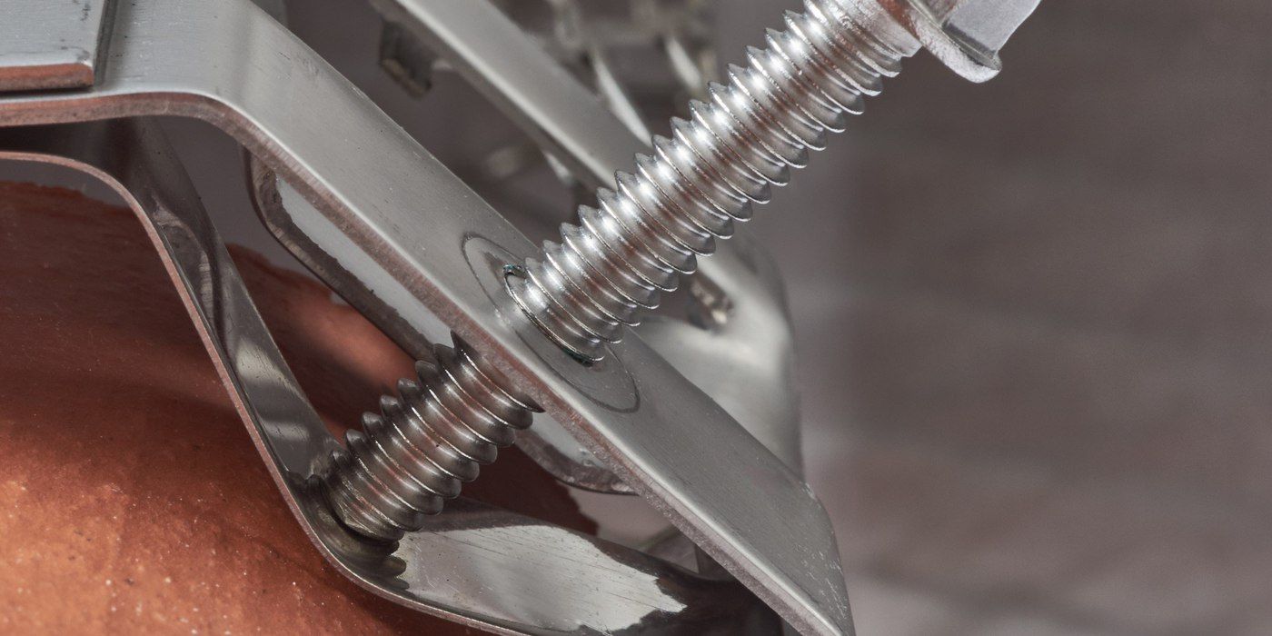 A close-up of the corner of a stainless steel bolt-on chimney cap being installed on a chimney flue tile