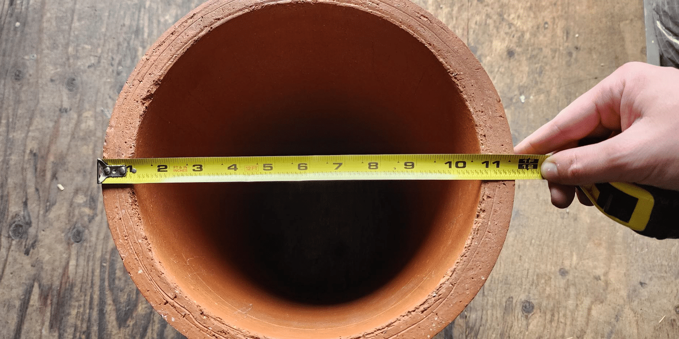 A round chimney flue pipe with a measuring tape measuring its diameter at 11.75 inches