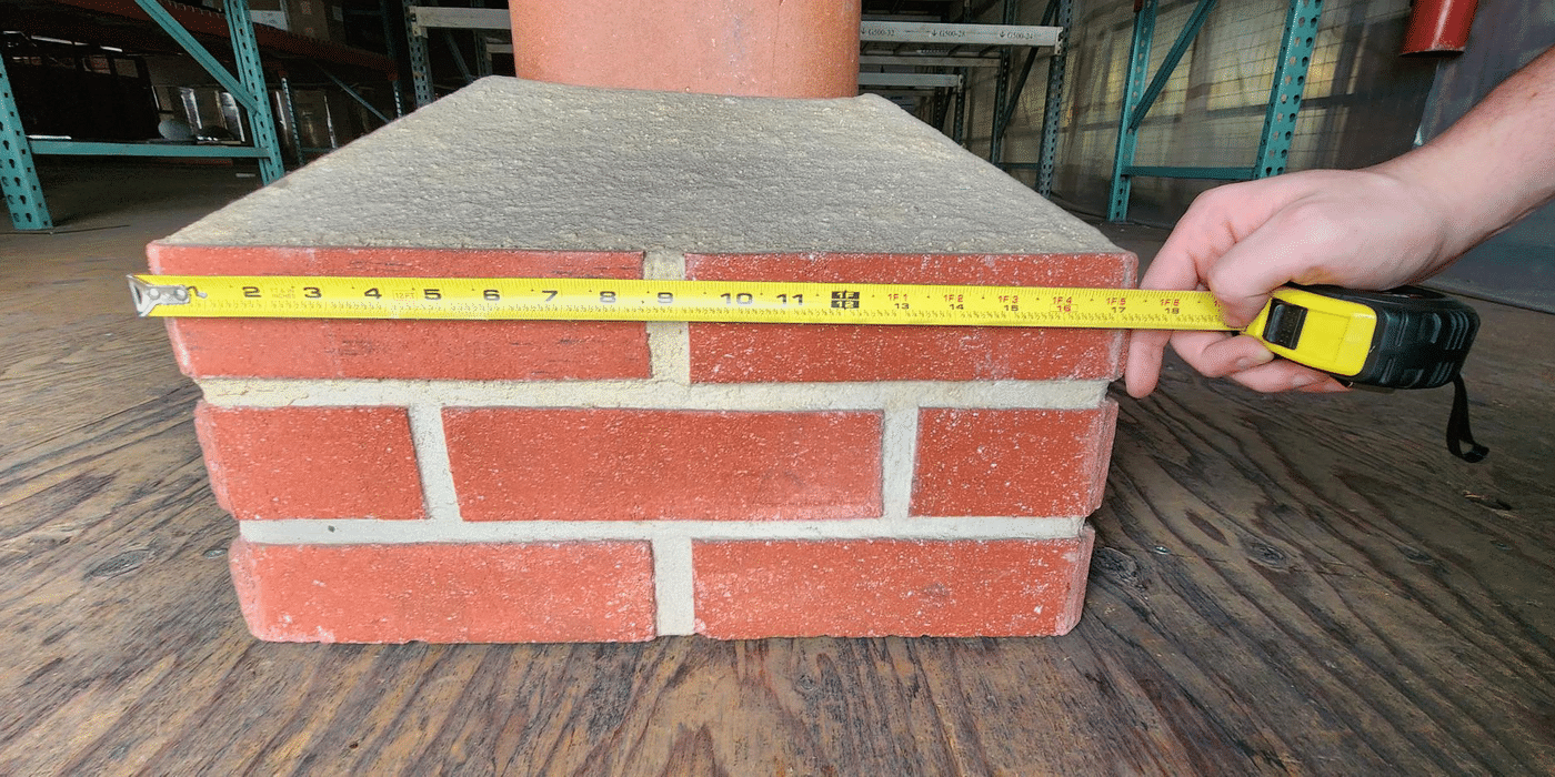 A prop chimney, crown, and flue with a tape measure across the top row of bricks measuring 17.5 inches