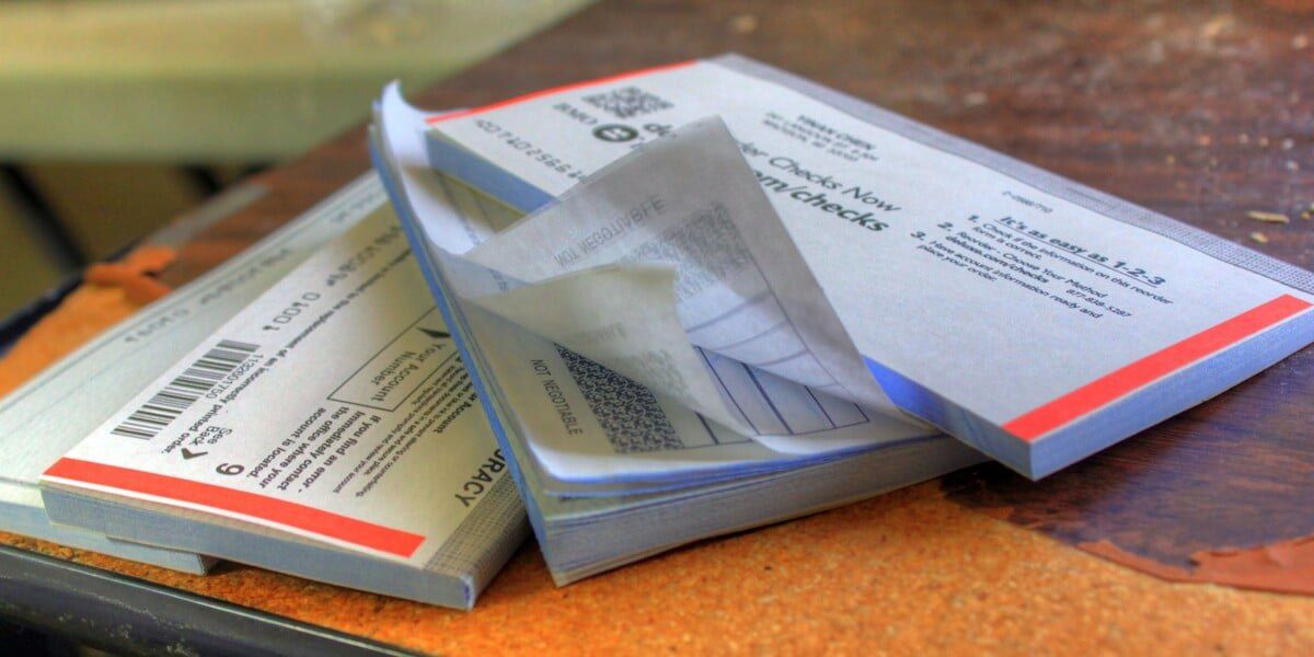 Four checkbooks stacked haphazardly on top of each other on a wooden table