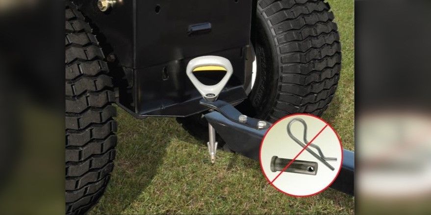 A Good Vibrations Quick-Connect Hitch Pin being inserted into the hitch of a lawn tractor.