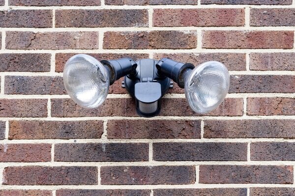 Motion sensor lights on brick wall in daylight
