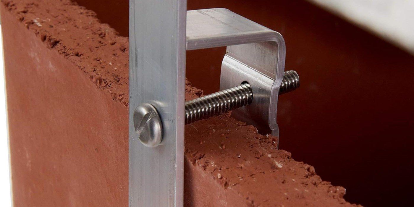 A close-up view of the braces of a multi-fit chimney cap attached to chimney flue tile and secured by a bolt