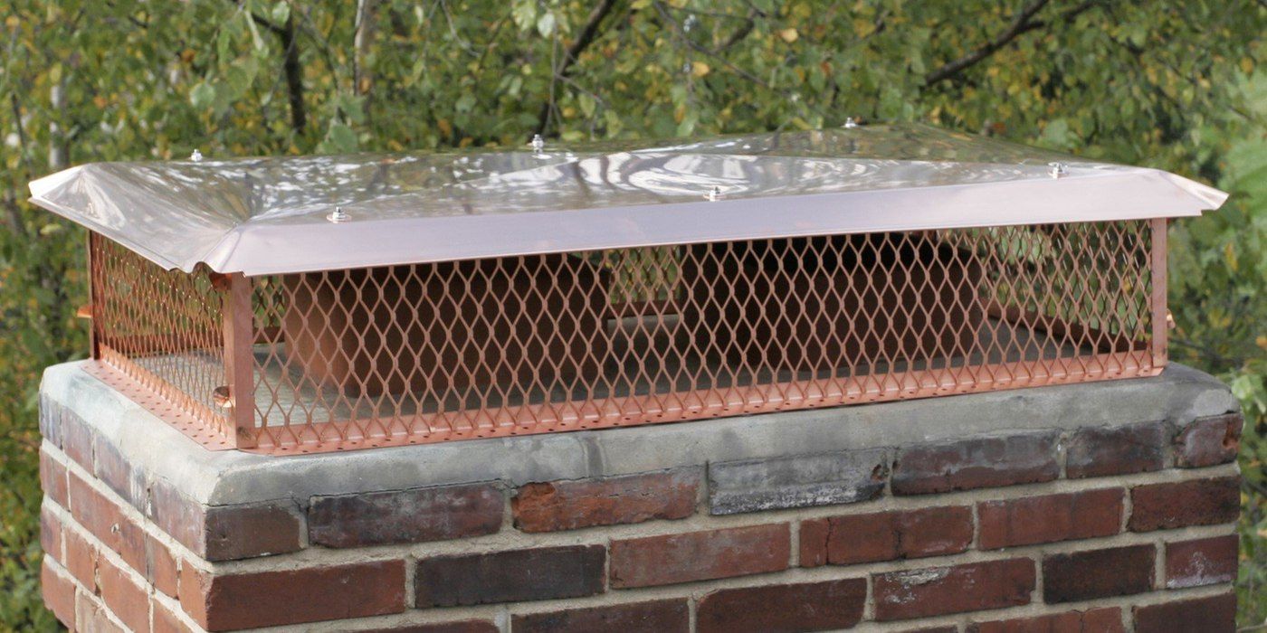 A multi-flue copper chimney cap installed on a chimney's crown