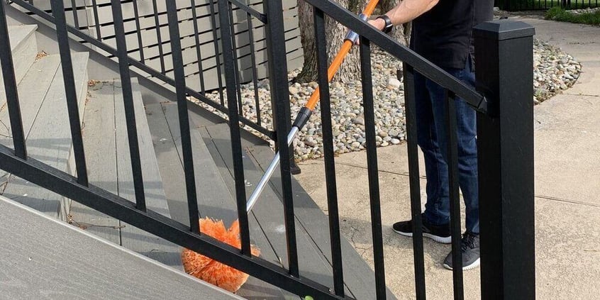 A man using a SpinAway drill brush to clean a patio staircase.