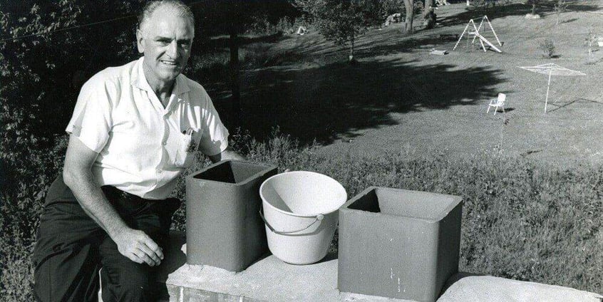 A black-and-white photo of Al Hisey, founder of HY-C, sitting on a multi-flue chimney with two flues. A bucket rests between both flues.