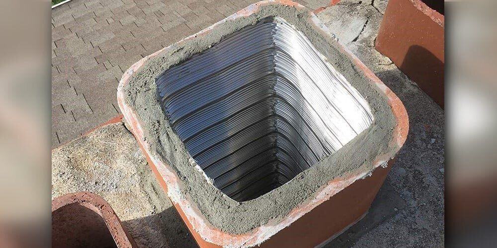 A square chimney flue liner installed in a chimney with concrete insulation between the liner and the flue pipe.