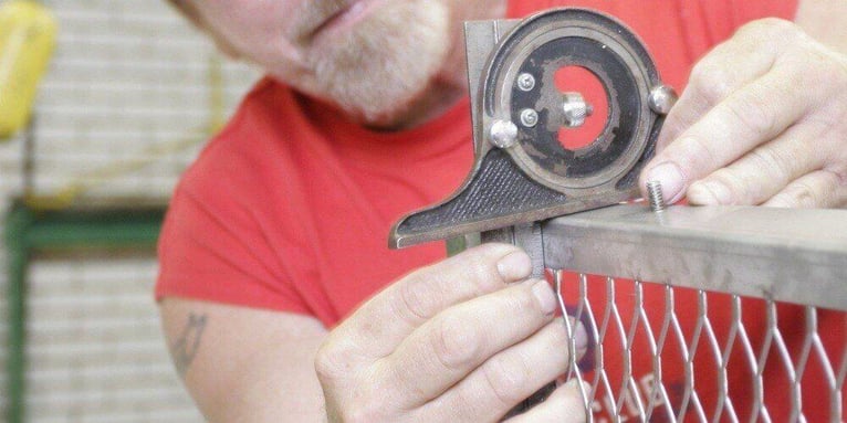 A man in a factory measuring the dimensions of a custom-made chimney cap.