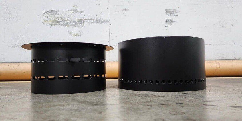 The top and base of a Flame Genie smokeless fire pit resting next to each other on a factory floor.