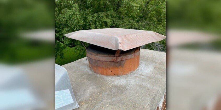 A rusted, round, aluminum chimney cap installed atop a round flue.