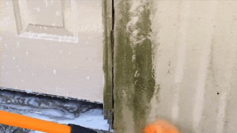 A GIF showing the Gardus SpinAway being used to clean green moss stains off of a corrugated metal wall
