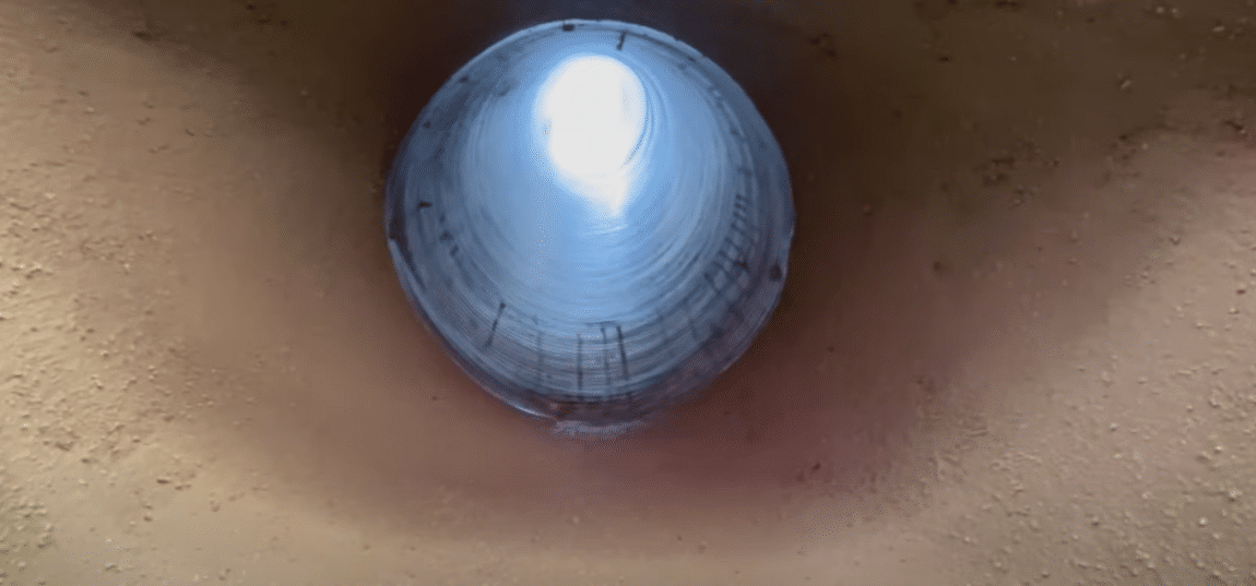 A bottom-up view of a round chimney liner parged onto a firebox
