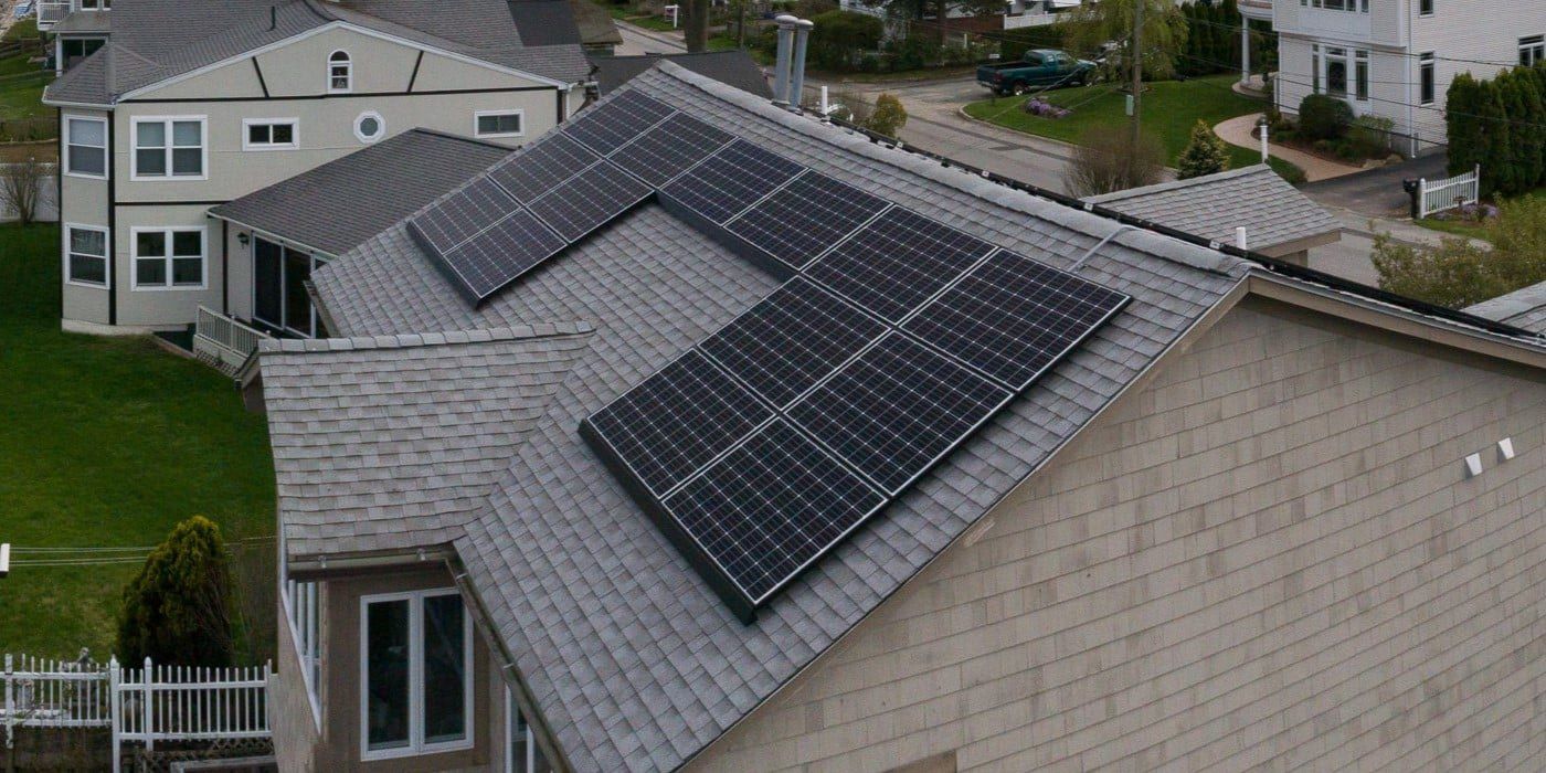 Solar panels installed on a roof with clay tile shingles with the sun shining in the top-left corner