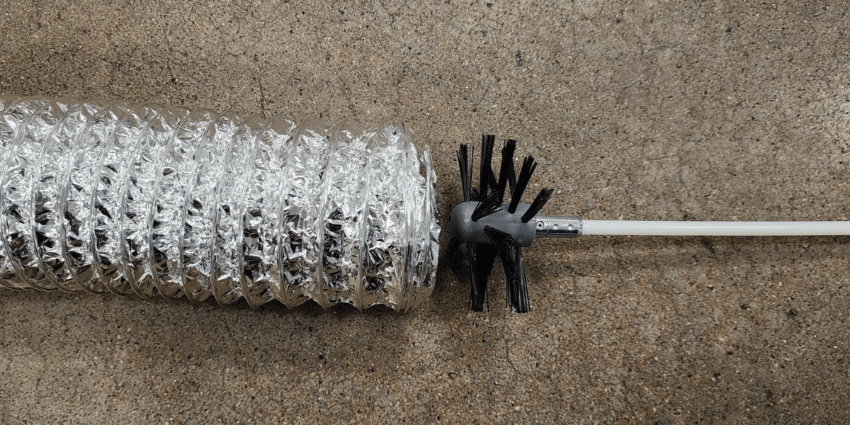 A dryer vent cleaning kit's auger brush head about to be inserted into a dryer vent hose