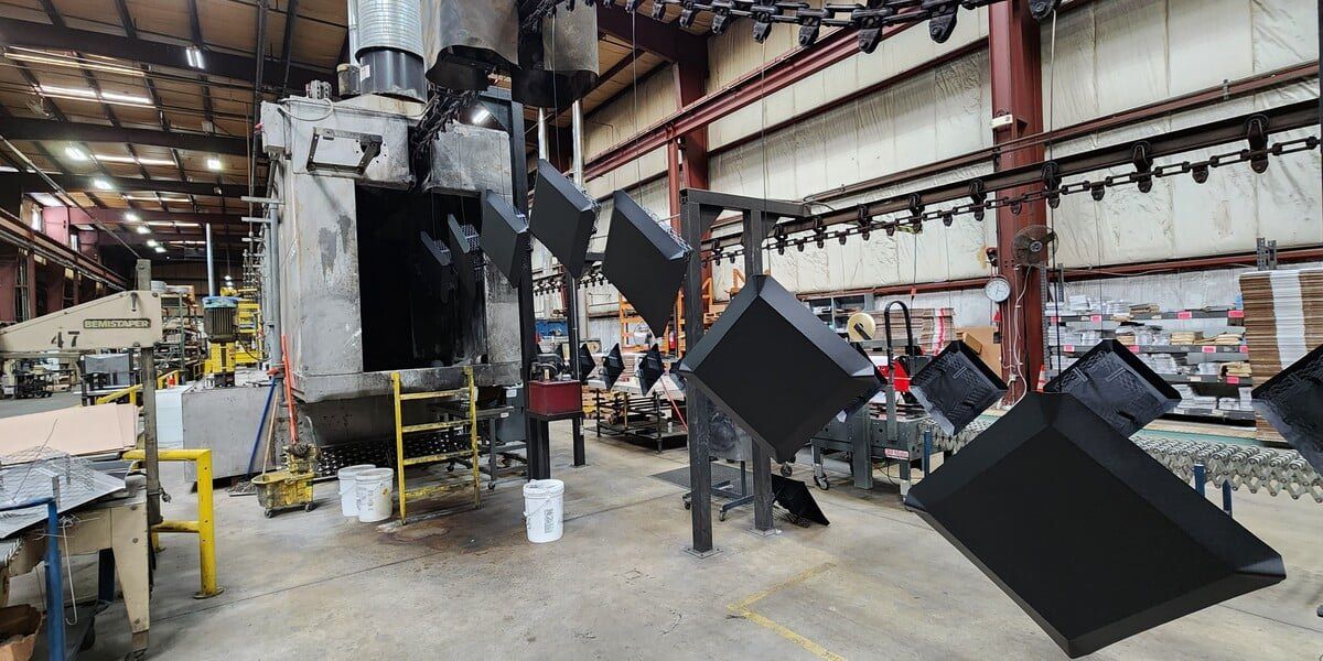 Black galvanized chimney caps going through the HY-C paint line on the factory floor