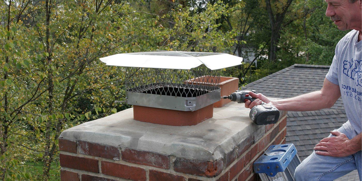 Roofer installing a stainless steel HY-C single-flue bolt-on chimney cap onto a chimney flue