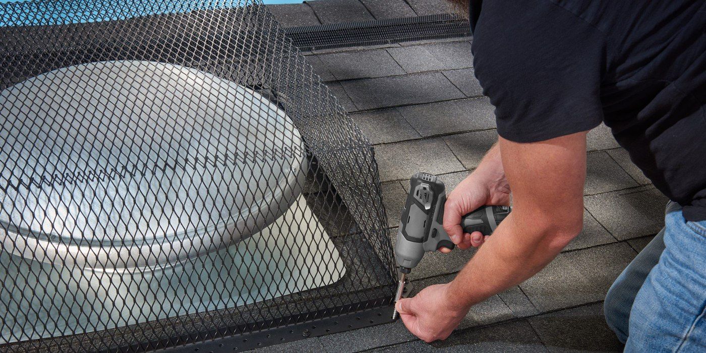 Roofing professional installing a HY-GUARD EXCLUSION roof vent guard on a roof with gray shingles