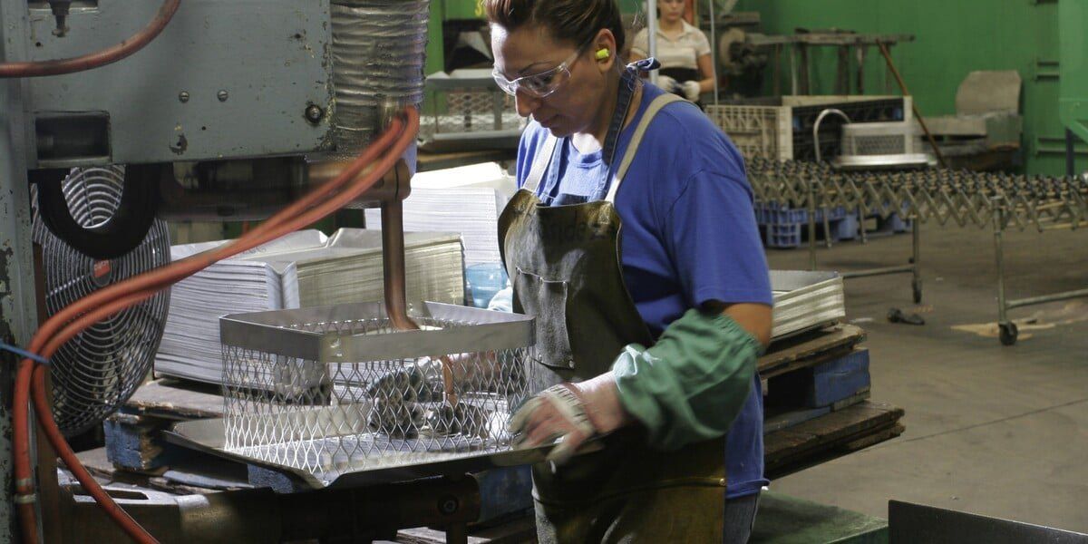 A female factory employee welding HY-C chimney caps on the factory machinery