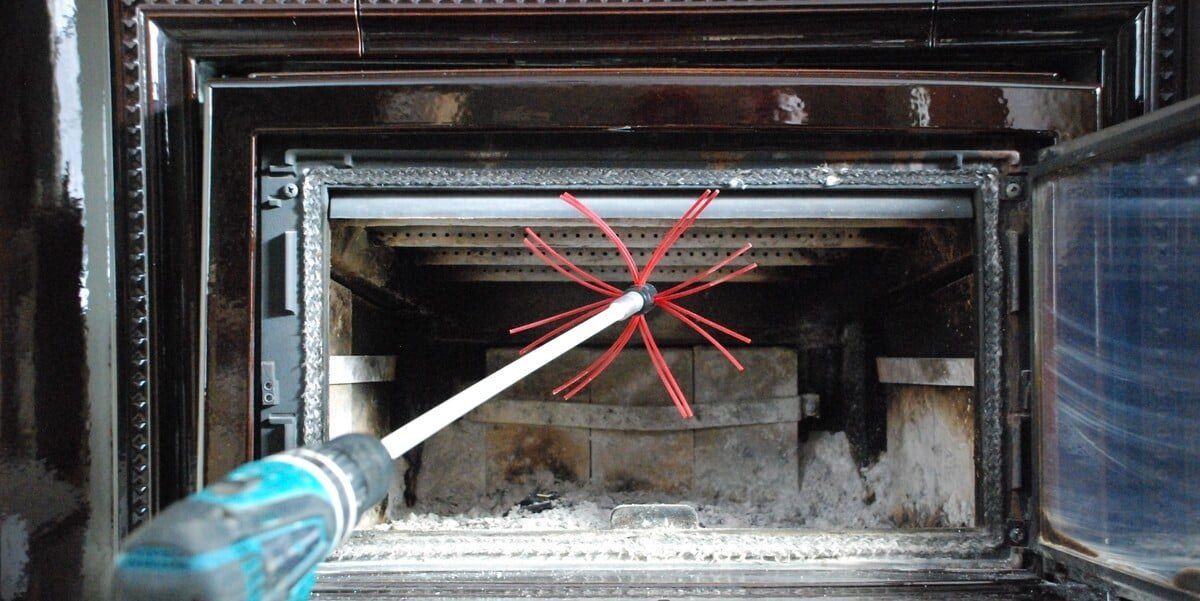 A SootEater rotary cleaning tool installed on a drill and sitting in front of an open fireplace