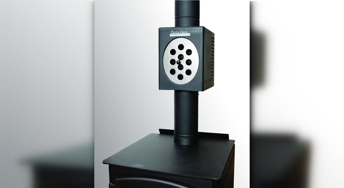 A Magic Heat heat reclaimer installed on a wood stove flue pipe on a black-to-white gradient background