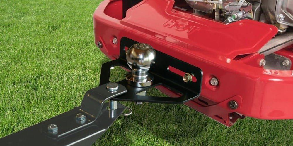 A Good Vibrations Z-Hitch Zero-Turn Hitchplate installed on a red zero-turn mower with green grass in the background