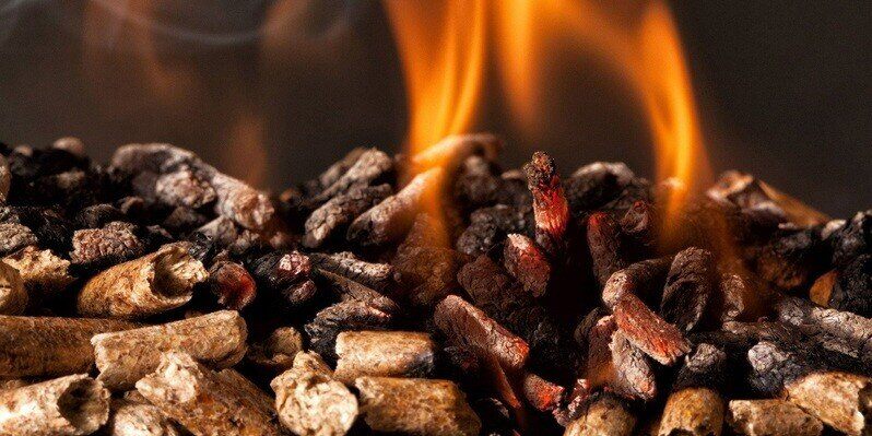 A closeup of a pile of wood pellet fuel. The pellets in the foreground are intact, while the pellets on the top of the pile are on fire.