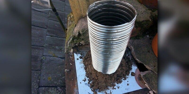 A round, flexible chimney liner being installed in a masonry chimney.