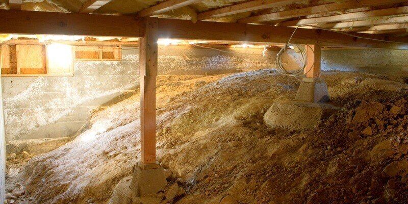 A wide shot of a crawl space. The beams that hold the home up are visible, as are the concrete walls and the home's floor joists.