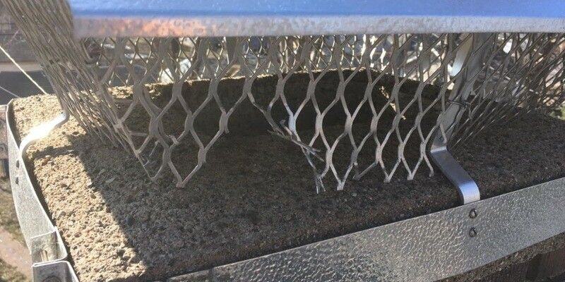 A Draft King Duro-Shield Band-Around-Brick Chimney Cap installed on a chimney. The cap's mesh has been chewed through by an animal.