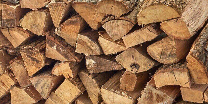 A closeup of firewood stacked on a rack, displaying the proper stacking method to achieve optimal seasoning and airflow.
