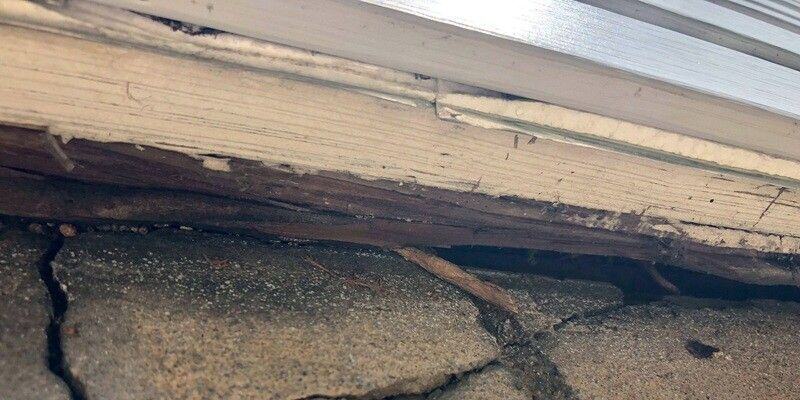 A close-up of the point at which the foundation of a home meets its siding. There is a clear gap between the siding and the foundation.