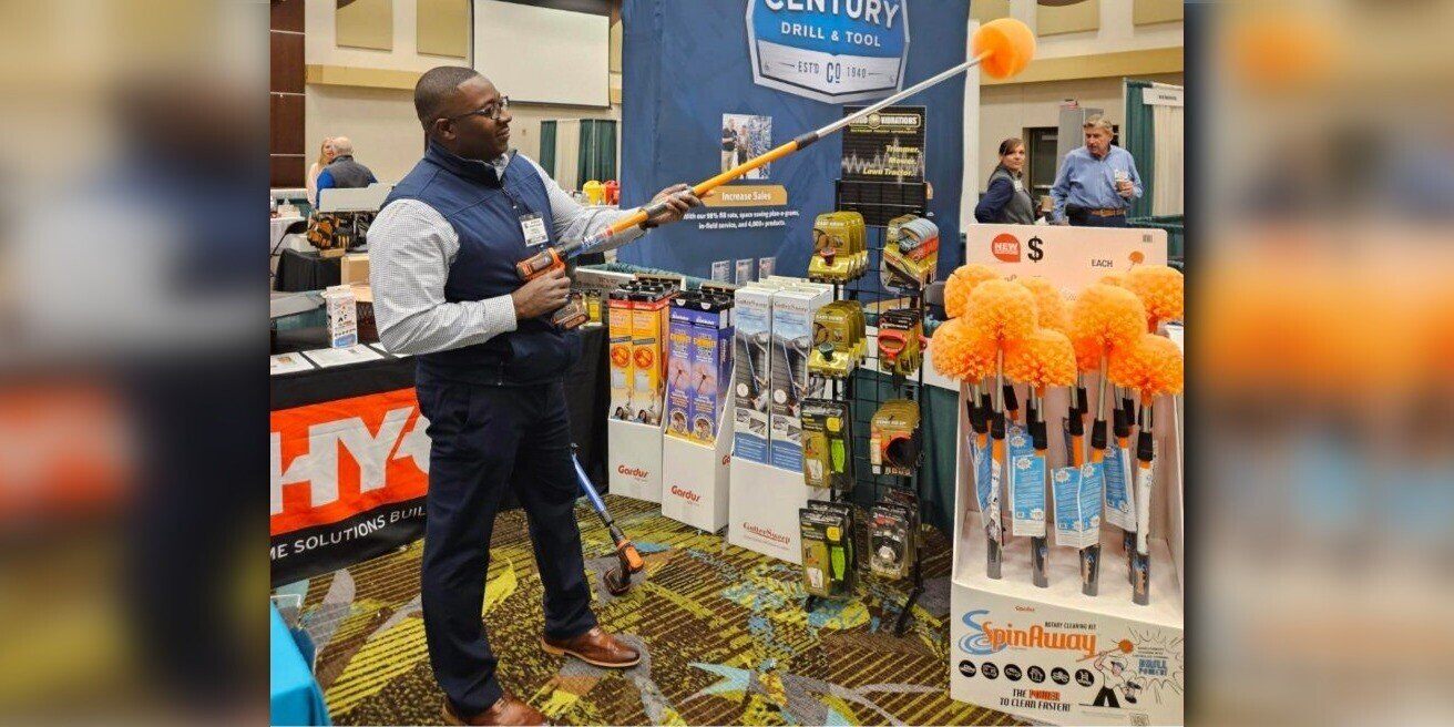 HY-C salesman Gerald Patterson using a SpinAway rotary cleaning tool on a tradeshow floor. Several HY-C products are on display behind him.