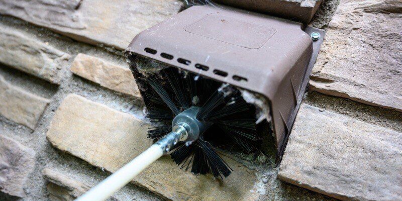 A Gardus LintEater by HY-C being used to clean a dryer vent that's covered by a hood-style dryer vent cover.