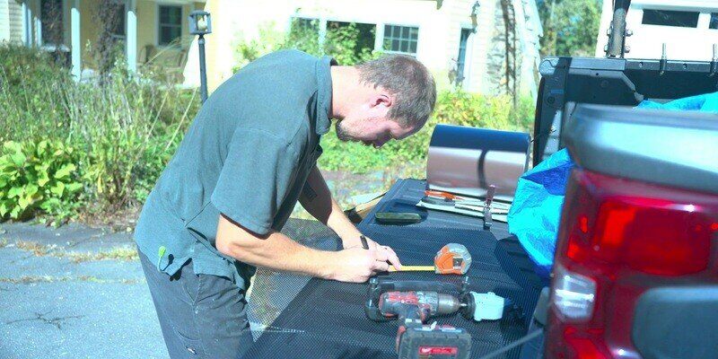 A man measuring a HY-GUARD EXCLUSION Pest Armor Tight Mesh Panel on the bed of his truck.