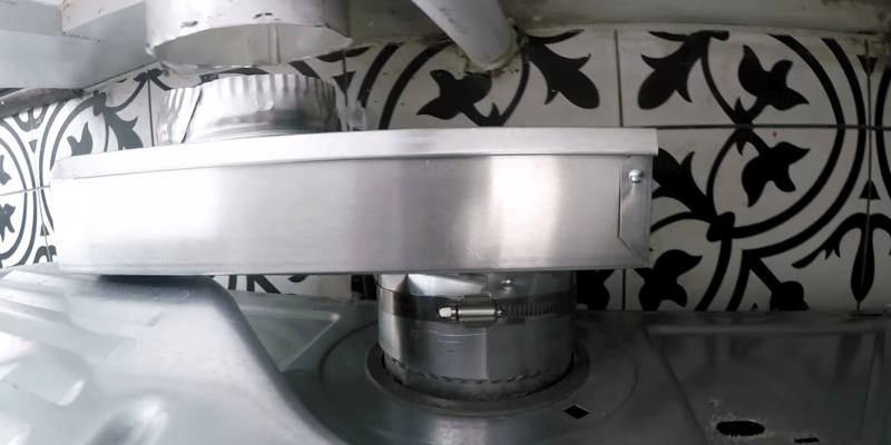 A periscope dryer vent installed on a dryer about to be pushed into the wall dryer vent.