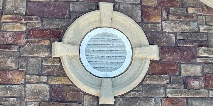 A HY-GUARD EXCLUSION Pest Armor panel installed on a gable end vent on a home with stone siding.