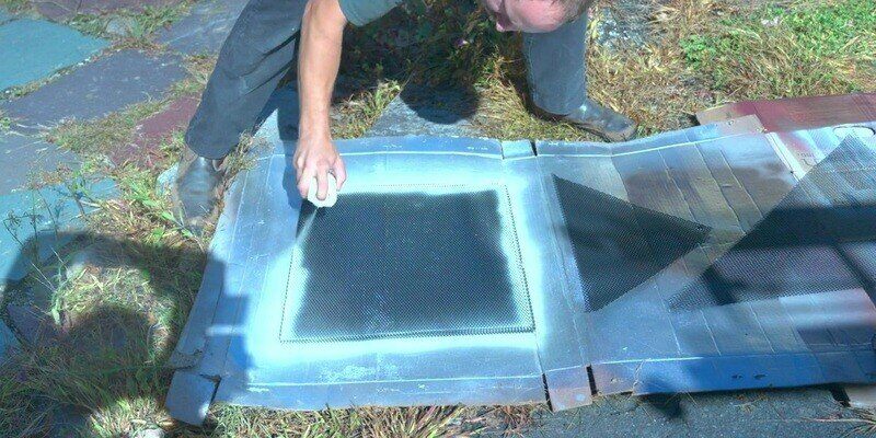 A man spray painting a few HY-GUARD EXCLUSION Pest Armor Tight Mesh Panels on the ground.