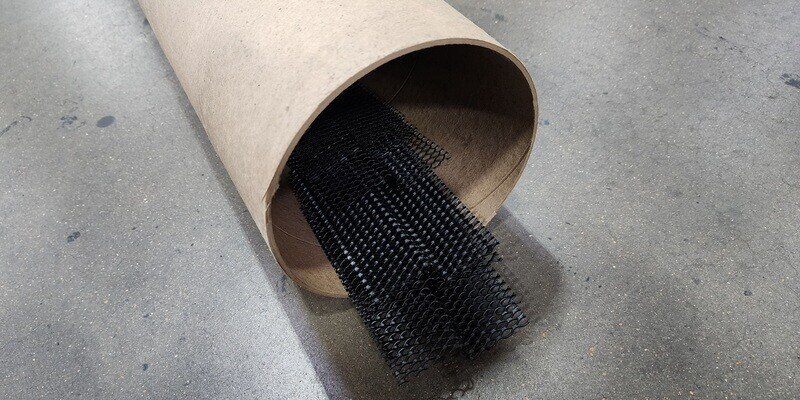 A tube of HY-GUARD EXCLUSION Pest Armor lying on a concrete factory floor. The Pest Armor is protruding slightly from the cardboard tube.