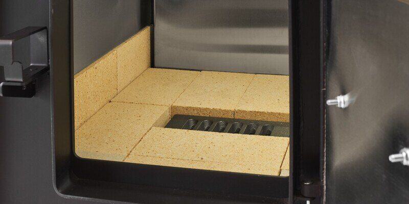 A close-up of the inside of the firebox of a Shelter SF1000E Wood Burning Furnace. The firebox is lined with HY-C firebrick.