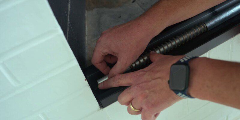 A man installing the spring end of the tension rod of a Liberty Foundry Co. Smoke Guard.