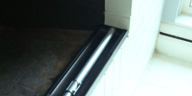A Liberty Foundry Co. Smoke Guard resting at the bottom of a white-bricked fireplace opening.