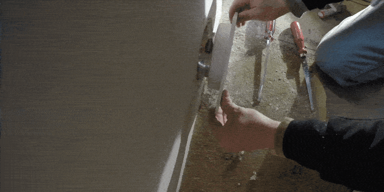 A man inserting the just connected backplate of a SnugDryer dryer vent connection kit into the drywall of a home.