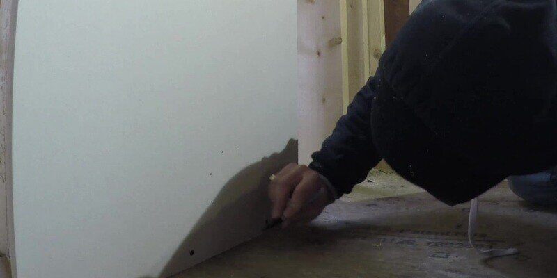A man marking the dimple imprints left by the dryer vent adapter piece of the SnugDryer dryer vent connection kit.