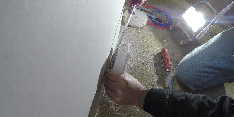A man attaching a hose clamp to hold the back plate of a SnugDryer dryer vent connector kit together with the in-wall dryer vent.