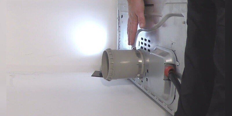 A closeup of the SnugDryer dryer vent connector kit's dryer vent adapter piece connected to the exhaust port of a dryer.