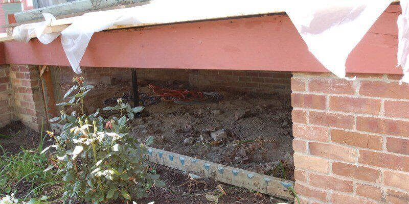 The inside of a front porch. The masonry has been stripped away, and the underside of the porch is fully visible.